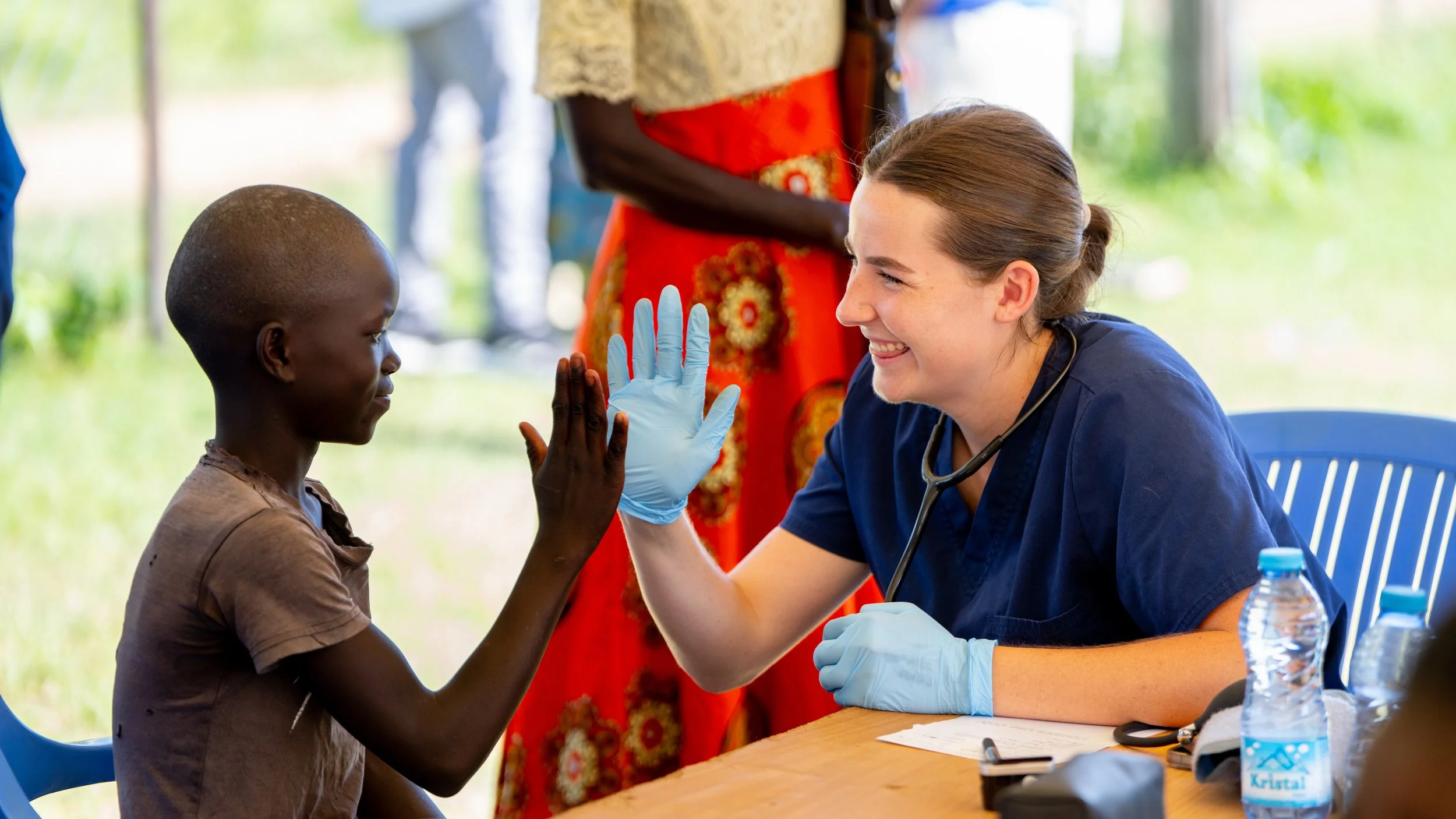 Healthcare worker high-fiving a child at a community clinic